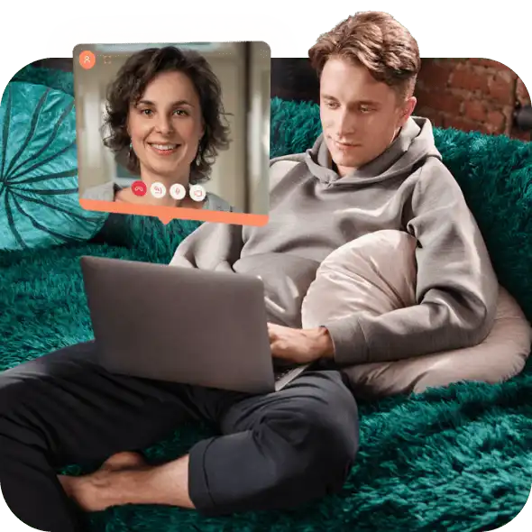 A young man sits on the sofa with his laptop and makes an appointment online for professional counselling service.